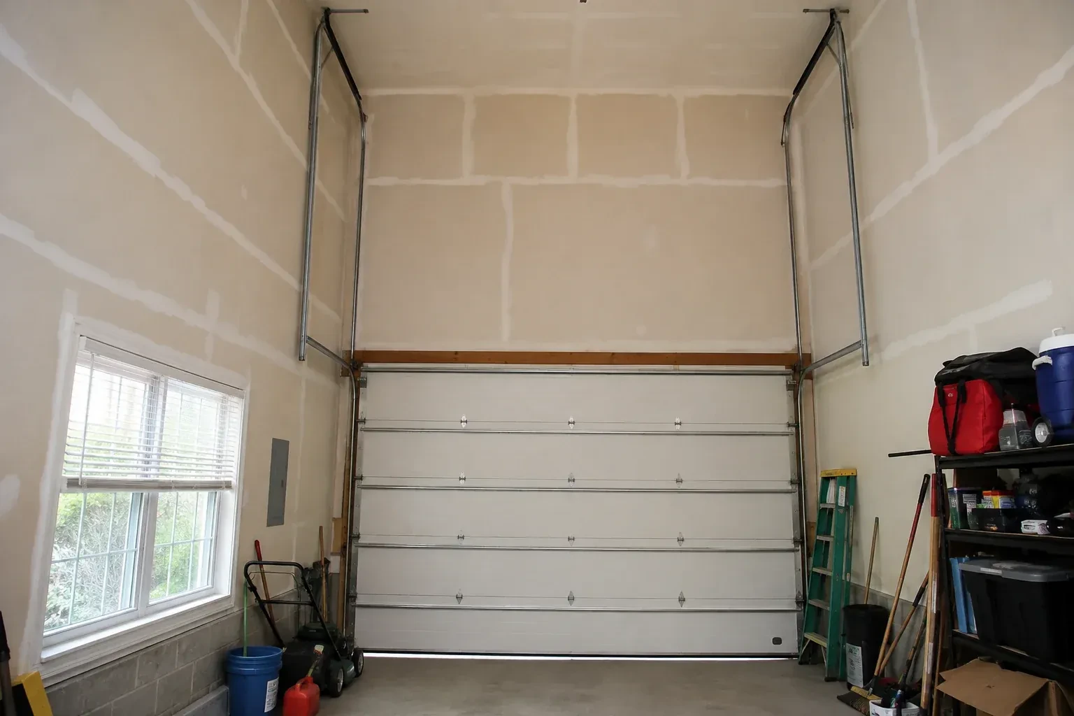 Tall garage interior with a sectional door and tracks extending into overhead space. — High-Lift Garage Door Conversion, Welland